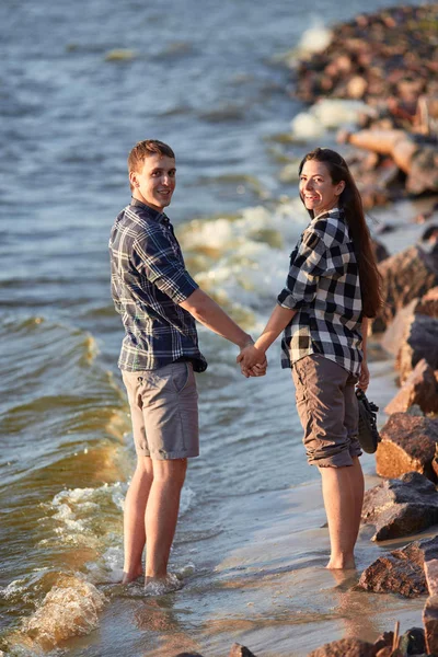 young couple in plaid shirts walking along the shore of the lake