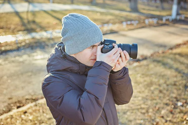 Photographer in a hat, makes a photo on his camera in the winter — Stock Photo, Image