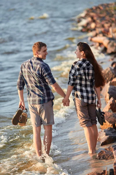 Ungt par i rutete skjorter som går langs bredden av innsjøen – stockfoto