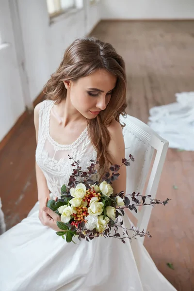 美丽的新娘在明亮的时尚工作室的婚纱。欧洲风格的婚礼。装饰和花束在手. — 图库照片