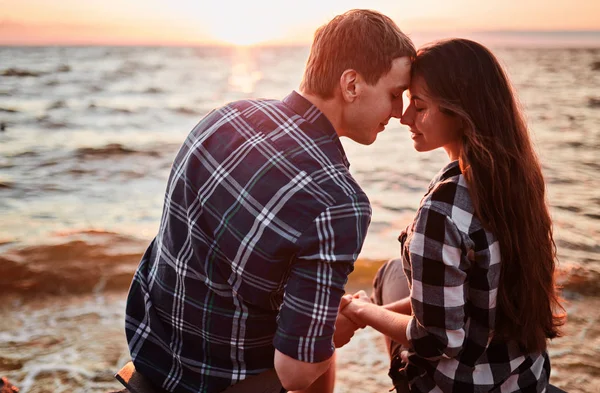 チェッカーのシャツを着た愛するカップルは、ラックの海岸に立っています — ストック写真