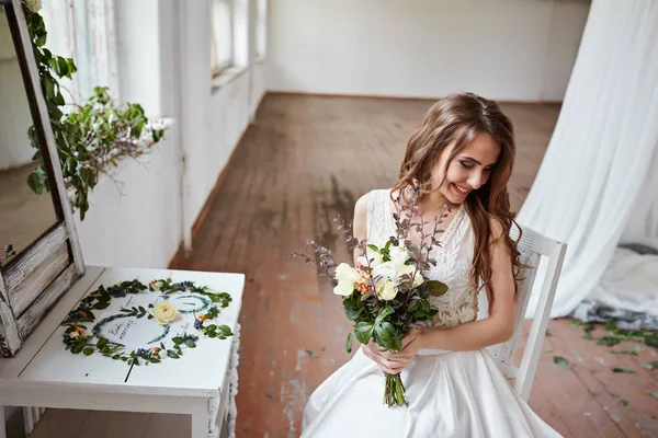 Bela noiva em um vestido de noiva em um estúdio elegante brilhante. Casamento em estilo europeu. Decoração e buquê na mão . — Fotografia de Stock