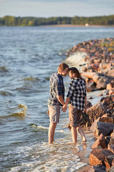 young couple in plaid shirts walking along the shore of the lake