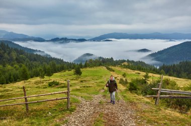 Adam ağır sırt çantası ile günbatımı dağlar, hiking