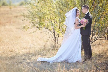 Bir buket çiçekli, düğün kıyafetli çift.