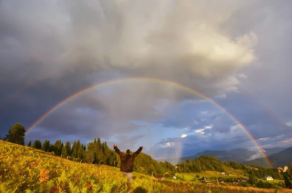 A happy man enjoys the rainbow in the mountains. — Stock Photo, Image