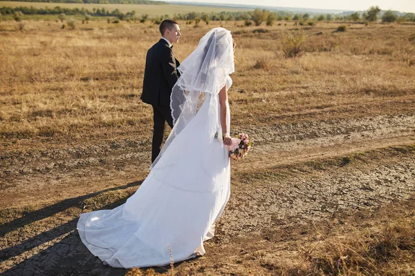 Casal em traje de casamento com um buquê de flores — Fotografia de Stock