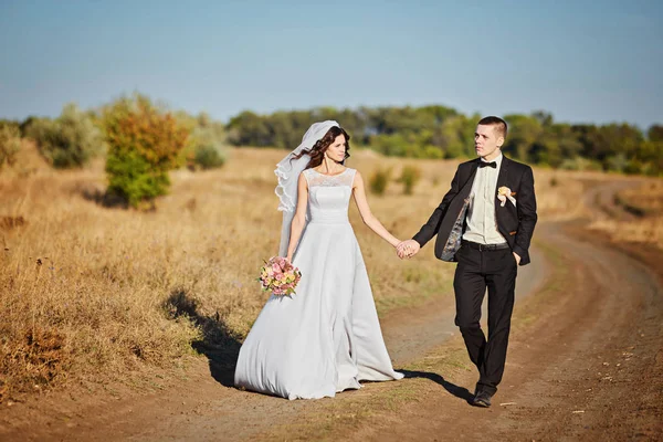 Paar im Hochzeitskleid mit einem Blumenstrauß — Stockfoto