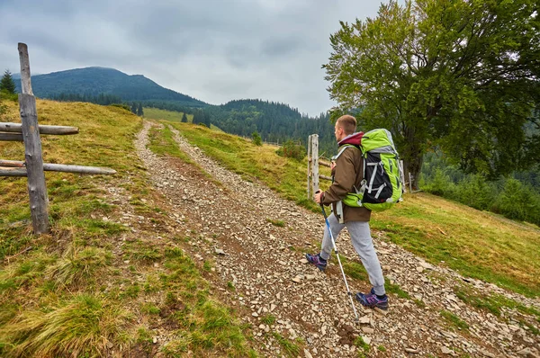 Man hiking at sunset mountains with heavy backpack