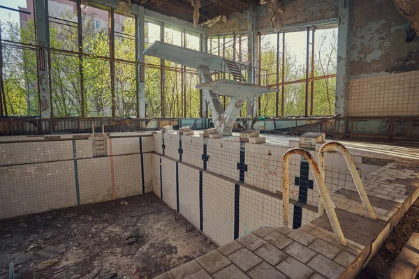 Piscina abandonada em Pripyat. Ginásio destruído numa cidade radioactiva. A rua está coberta de árvores e arbustos . — Fotografia de Stock
