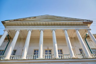 The grand classical facade of the Halagan Palace in Sokyryntsi, Ukraine, featuring a columned entrance, ramp, and statues under a clear blue sky. Historic estate.