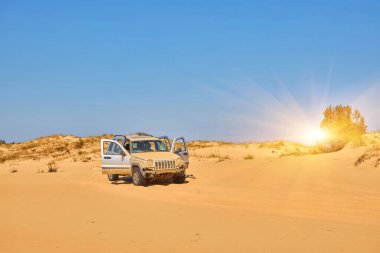 Kapıları açık kum tepelerine park etmiş bir off-road aracı. Off-road macera ve seyahat konsepti. Açık mavi gökyüzü.