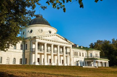 Majestic classical facade of Kachanivka Palace in Ukraine, showcasing its grand colonnaded portico and central dome against a clear blue sky. Historic landmark.