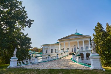 The grand classical facade of the Halagan Palace in Sokyryntsi, Ukraine, featuring a columned entrance, ramp, and statues under a clear blue sky. Historic estate.