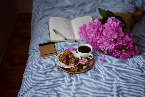Ay çöreği, kahve fincanı ve yatakta peonies buket
