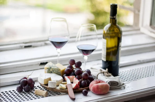 チーズの盛り合わせと窓枠にワインとグラス — ストック写真