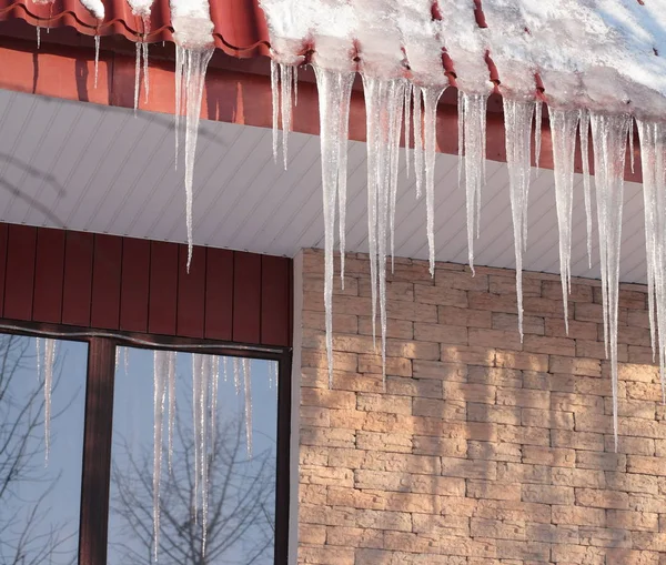 在阳光明媚的冬日建筑屋面上的冰柱 — 图库照片