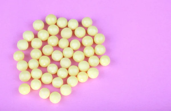Yellow vitamins on pink background — Stock Photo, Image
