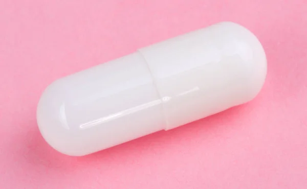 Białe tabletki na różowym tle — Zdjęcie stockowe