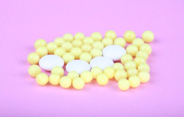 pembe bir arka plan üzerinde sarı vitaminler