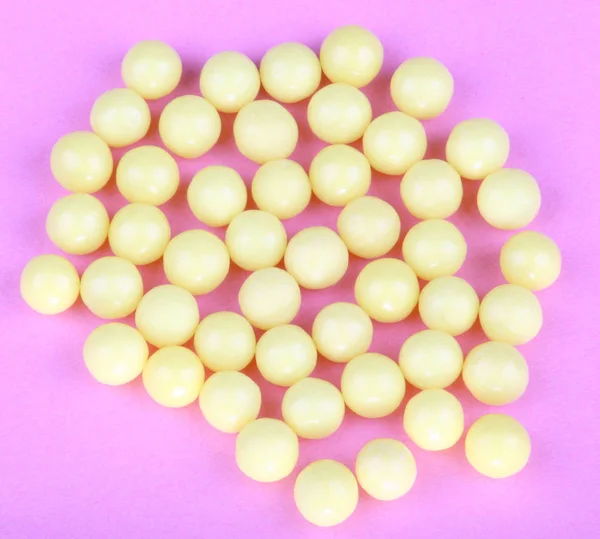 Pembe bir arka plan üzerinde sarı vitaminler — Stok fotoğraf