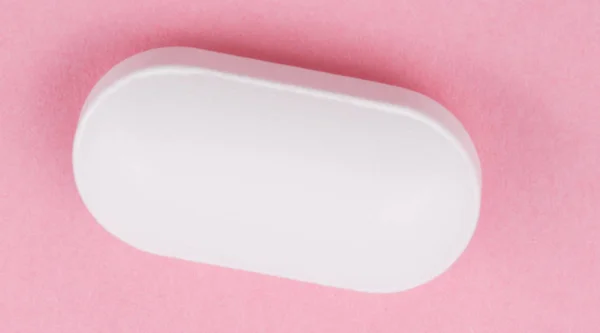 Pillola bianca su sfondo rosa — Foto Stock