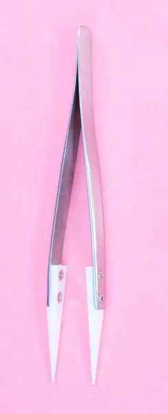Стальной керамический пинцет на розовом фоне — стоковое фото
