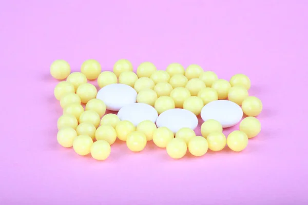 Yellow vitamins on pink background — Stock Photo, Image