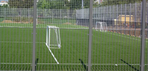 Güneşli bir günde çitin yanında futbol sahası — Stok fotoğraf