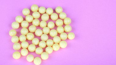 pembe bir arka plan üzerinde sarı vitaminler