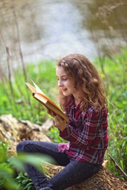 Neşeli kız doğada bir kitap okuyor