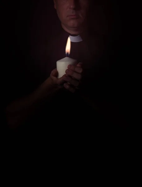 Priest prays with a candle