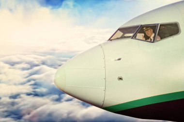 Yükseklerde uçağın kokpitinde gülümseyen pilot.