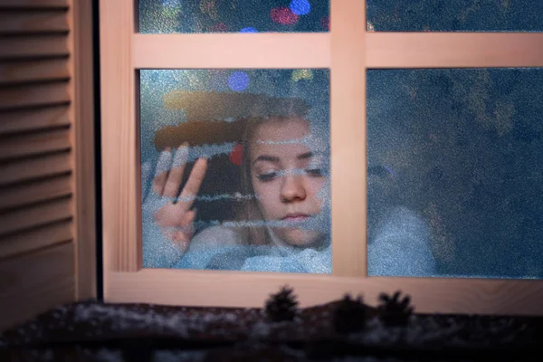 Einsames Und Trauriges Mädchen Blickt Winterabend Aus Dem Fenster — Stockfoto