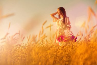 Gün batımında buğday tarlasında genç bir kadın