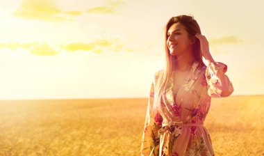 Gün batımında buğday tarlasında genç bir kadın