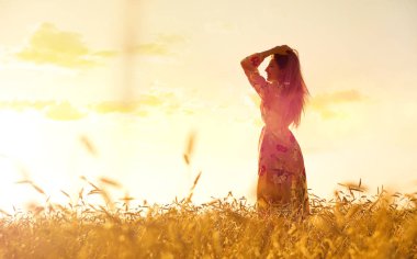 Gün batımında buğday tarlasında genç bir kadın