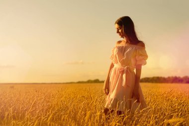 Gün batımında buğday tarlasında genç bir kadın