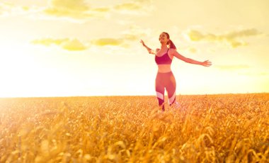 Gün batımında buğday alanında sportif kadın