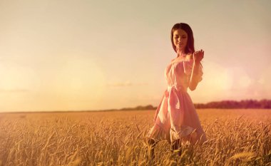Gün batımında buğday tarlasında genç bir kadın