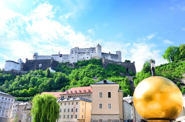Schöner blick auf hohensalzburg und berühmter mann auf goldenem kugeldenkmal am platz in salzburg — Stockfoto