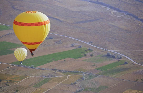 Два Жёлтых Воздушных Шара Летящих Над Землей — стоковое фото