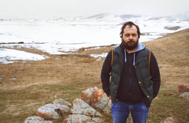 Kış bozkırındaki bir adam kameraya bakıyor.