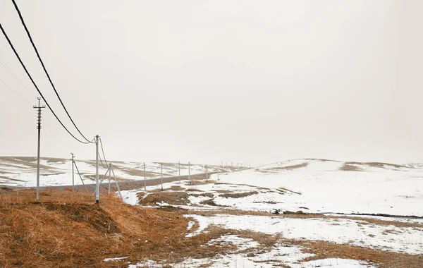 Winterfeld mit Stromleitungssäulen — Stockfoto