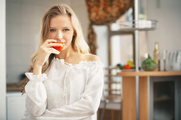 Blond dametje met rijpe tomaat in de keuken — Stockfoto