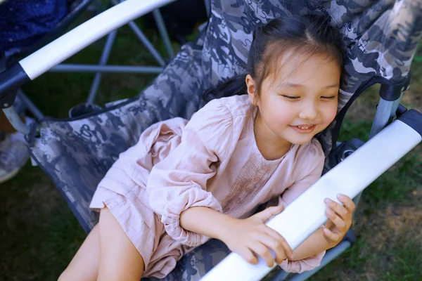 笑着女孩坐着，在折叠椅上放松 — 图库照片