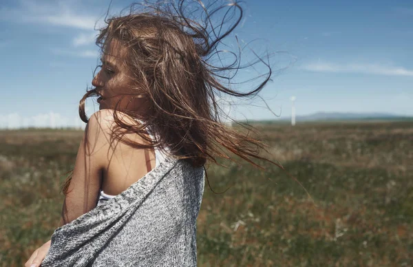 Kvinna med långt rufsigt hår bredvid vindkraftverk med w — Stockfoto