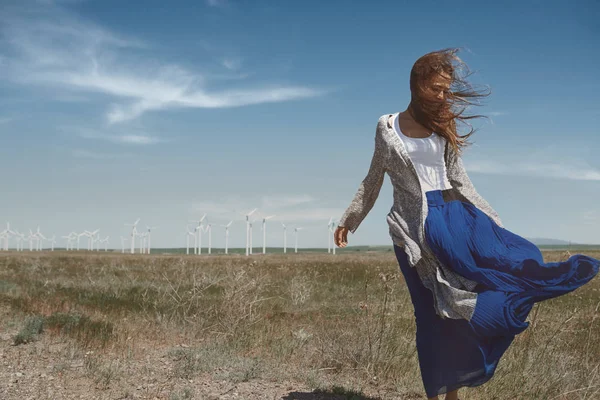Vrouw met lang tousleed haar naast de windturbine met de w — Stockfoto