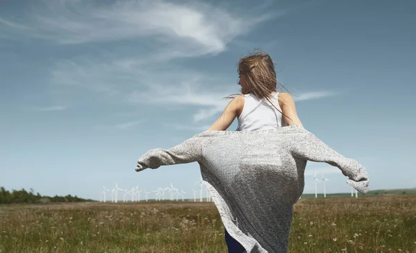 Woman with long tousled hair next to the wind turbine with the w — Stock Photo, Image