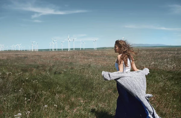 Mulher com longos cabelos desarrumados ao lado da turbina eólica com o w — Fotografia de Stock